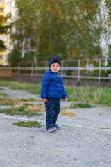 Fototapeta premium Spring walk in the park of the child. Autumn, off-season, a boy in a jacket and hat. life style.