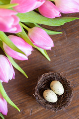 tulpen mit nest und eiern auf braunem holztisch