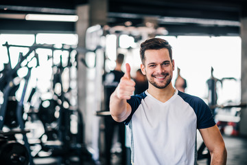 Athlete showing thumbs up in the gym, looking at camera.