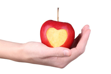 Female hands holding red apple with cutout heart shape on white background