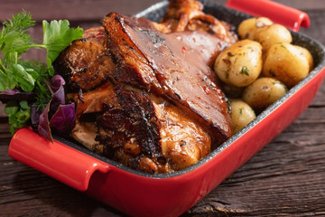 Close up roast pork knuckle served with boiled potatoes in tray