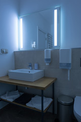 hotel bathroom with washstand and towels with neon light on mirror