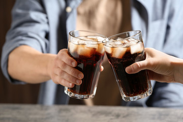 Couple with glasses of cold cola at table, closeup
