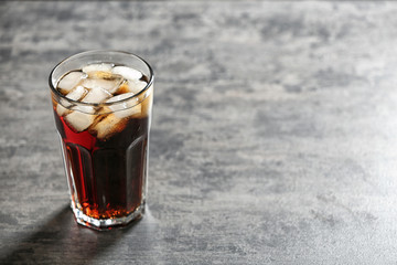 Glass of cold cola on grey table. Space for text