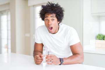 African American man drinking a glass of water at home scared in shock with a surprise face, afraid and excited with fear expression