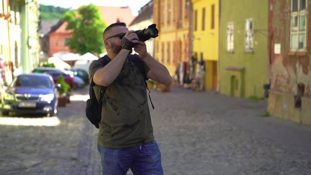 Man walking in the old town and doing photos on the camera 