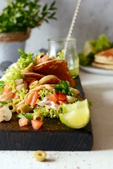 Unsweetened pancakes with turkey, lettuce, tomatoes, pickled mushrooms, olives and greens in the form of tacos on a wooden board. tasty snack of their pancakes and vegetables. Healthy eating concept