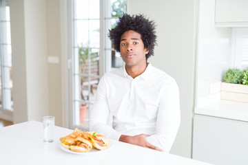 Fototapeta na wymiar African American hungry man eating hamburger for lunch with serious expression on face. Simple and natural looking at the camera.