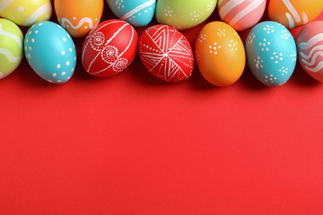 Flat lay composition of painted Easter eggs on color background, space for text