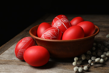Wooden bowl with red painted Easter eggs on table