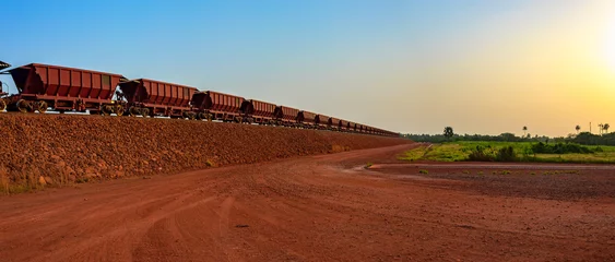 Gartenposter Eisenbahnwaggons zum Transport von Bauxiterz auf Bahngleisen am Ende der Bahnstrecke aus dem Bauxitbergbau. Guinea, Afrika. © Igor Groshev