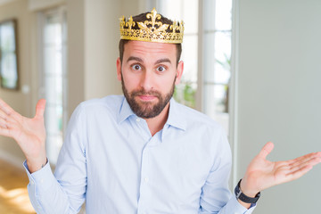 Handsome business man wearing golden crown as a king or prince clueless and confused expression...