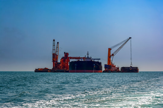 Loading ocean-going bulk carrier ship with Bauxite aluminum ore from the mini bulk carrier (feeder) vessel at offshore Kamsar port, Guinea, West Africa.