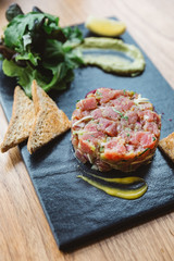 Close up Spicy Bluefin Tuna Tartare with sour and spicy sauce. Served with toast and salad on black...
