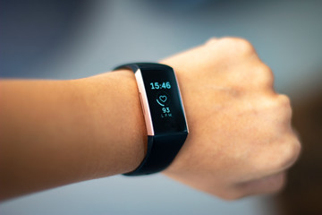 Woman monitoring her heart beat with an activity tracker wearable device on her wrist also known as...