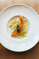 Top view of Ravioli in cream sauce with Grilled Salmon topping with Caviar.