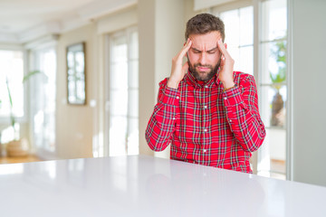 Handsome man wearing colorful shirt with hand on head for pain in head because stress. Suffering migraine.