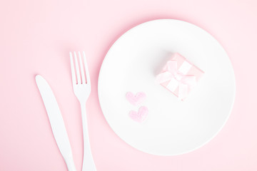 Festive table setting for Valentines Day with fork, knife and hearts  on pink pastel background.Romantic dinner. Space for text. Top view.