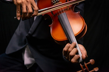 Closeup playing violin on a dark background.