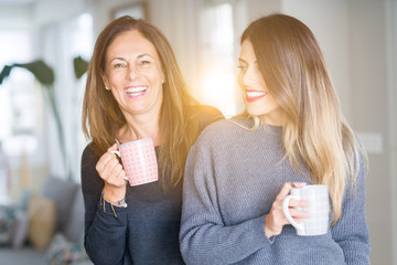 Beautiful family of mother and daughter together drinking a cup of coffee at home