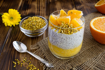 Pudding with chia, orange and  bee pollen on the rustic wooden background