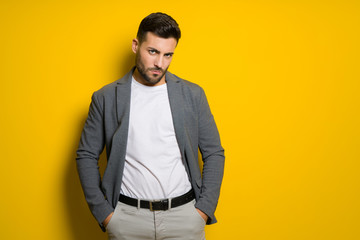 Fototapeta premium Young handsome man possing and modeling over yellow isolated background