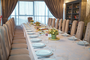Table with empty plates and glasses in the restaurant . Crystal wine glasses on a served banquet table with salads and snacks