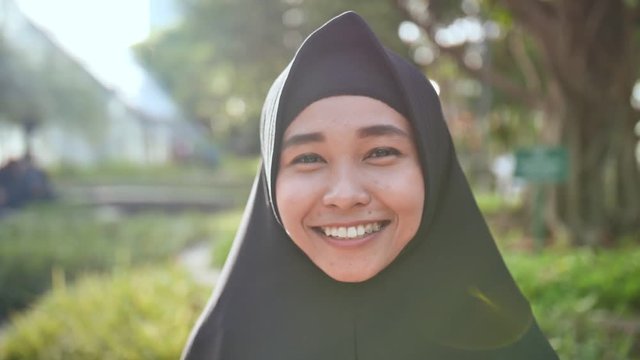 Portrait of a young smiling Muslim girl in a black hijab.