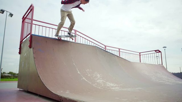 Casual young man skateboarding on ramp in slow motion performing simple trick