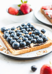 Close-up of breakfast sweet toast with chocolate spread, blueberry and crashed almond.