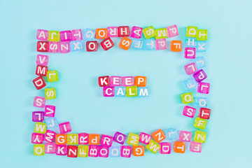 Keep calm inscription made of colorful cube beads with letters. Festive blue background concept with copy space