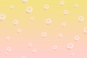 Summer fruit pattern. Flying banana slices on yellow to pink pastel gradient background. Minimal summer concept.