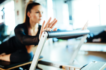Two young females doing reformer exercises on pilates machines