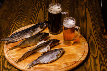 Beer glass with beer on a background of dried fish on a wooden table in a rustic style.