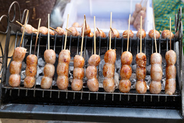 Thai sausage (Thai name  Sai Krok Isan), made from mince pork, rice. Mix all together, stuffed in pork chitterlings,Thai sausage on the stove. Thailand street food. pork sausage served with vegetables