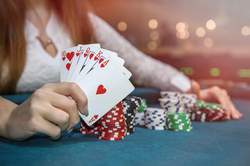 Poker chips and female hands holding playing cards
