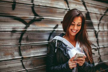 Young happy woman using smartphone on the street