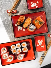 Various kinds of sushi and rolls served on red plate