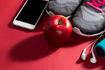 Pair of sport shoes, apple, meetr and towel on red background. Copy space. Flat lay – image