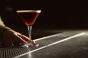 Barman serving espresso martini cocktail at counter, closeup. Space for text