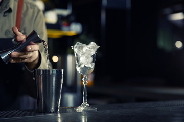 Barman pouring martini into shaker on counter, closeup with space for text