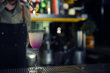 Barman adding lemon zest into cosmopolitan martini cocktail at counter, closeup. Space for text