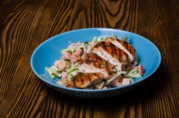 Mix sausage with fried potato and salad on wooden background