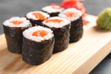 Tasty sushi rolls on wooden board, closeup. Food delivery