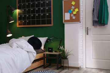 Modern teenager room interior with comfortable bed against green wall
