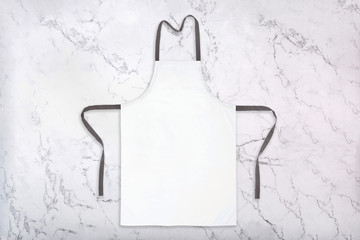 Mockup of white apron on marble background. Chef uniform template. Flat lay