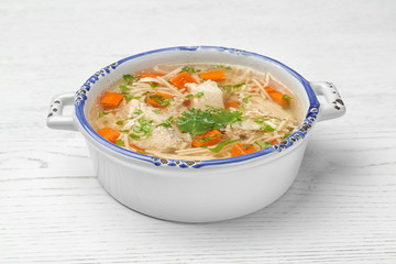 Dish with fresh homemade chicken soup on wooden background