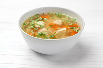 Bowl with fresh homemade chicken soup on wooden table