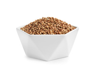 Bowl with uncooked buckwheat on white background