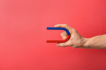 Man holding magnet on color background, closeup. Space for text